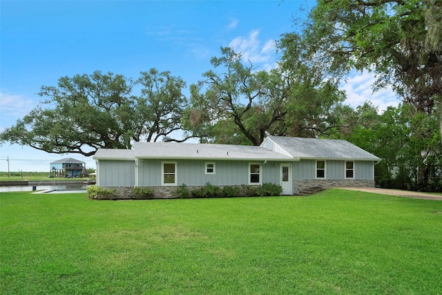 view of front of house featuring a front lawn, stone siding, and board and batten siding
