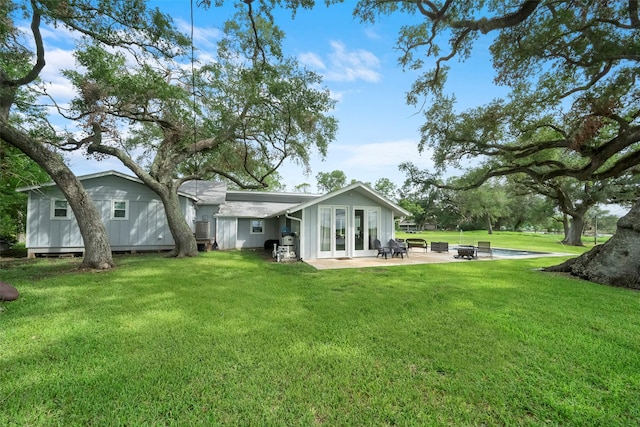 back of house with a yard, a patio area, and an outdoor fire pit