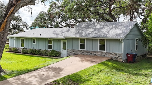 ranch-style house with a front lawn, roof with shingles, stone siding, and board and batten siding