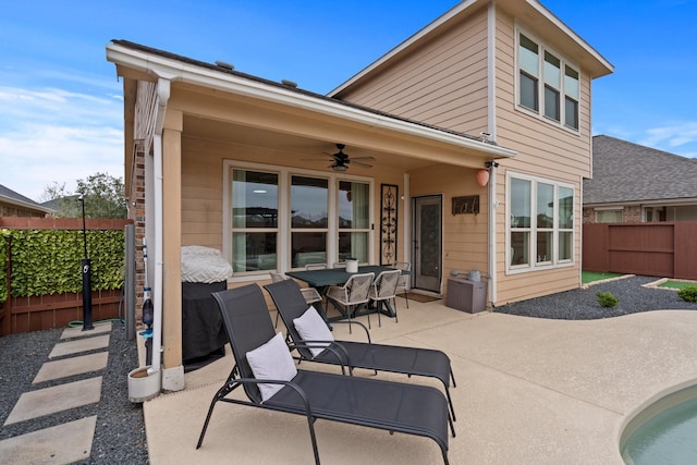rear view of house with a ceiling fan, a fenced backyard, a patio, and outdoor dining space