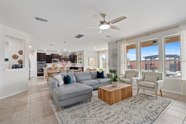 living room with visible vents, light tile patterned floors, and ceiling fan with notable chandelier