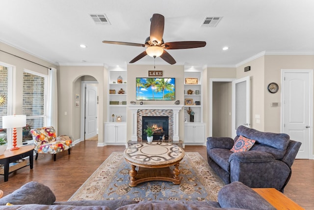 living room with arched walkways, wood finished floors, visible vents, and ceiling fan