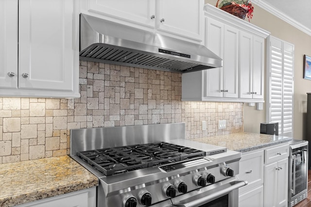 kitchen with white cabinets, under cabinet range hood, wine cooler, crown molding, and high end range