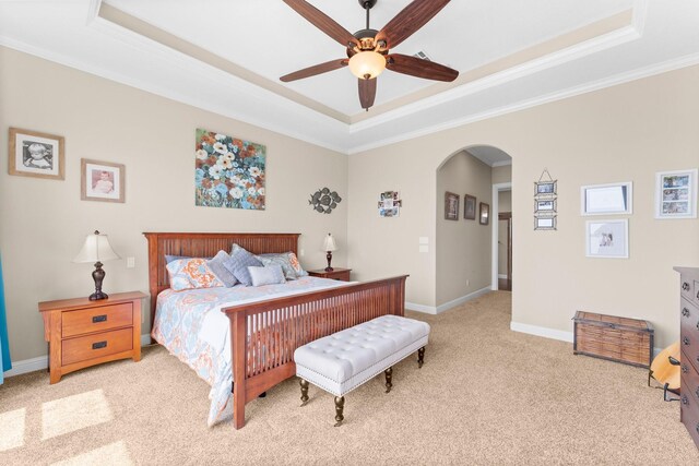 carpeted bedroom with a raised ceiling, a ceiling fan, ornamental molding, arched walkways, and baseboards