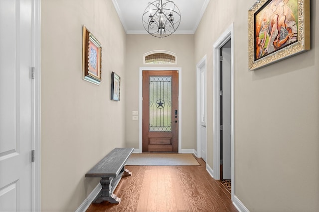 doorway to outside with wood finished floors, ornamental molding, baseboards, and a notable chandelier