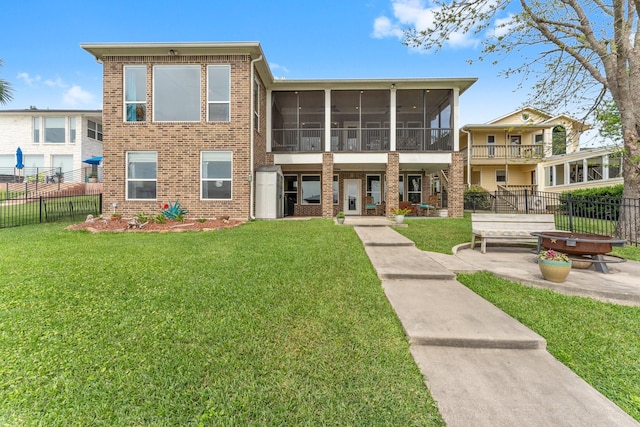 exterior space featuring a lawn, a sunroom, a patio area, and brick siding