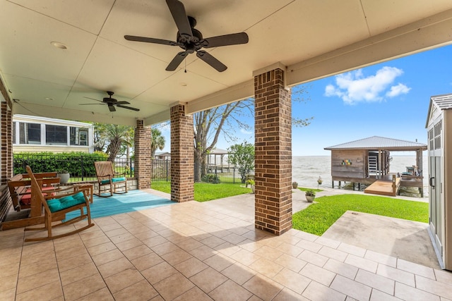 view of patio featuring fence, a water view, and a ceiling fan