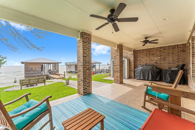 view of patio / terrace featuring ceiling fan, area for grilling, and a water view