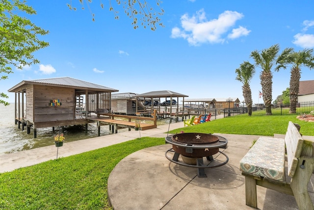 view of community featuring a patio area, a lawn, a boat dock, a fire pit, and fence