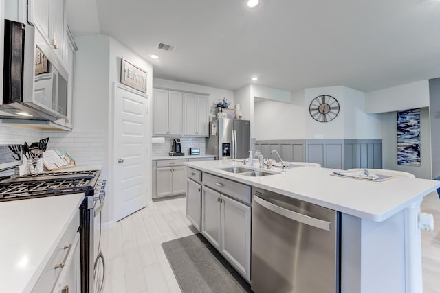 kitchen featuring stainless steel appliances, a sink, visible vents, decorative backsplash, and light countertops