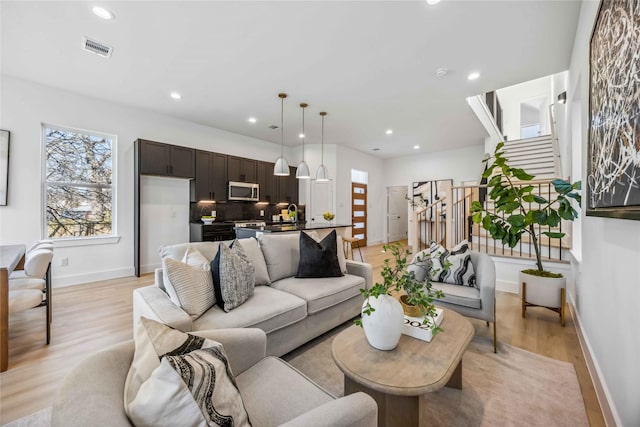 living room with recessed lighting, baseboards, visible vents, and light wood-style flooring