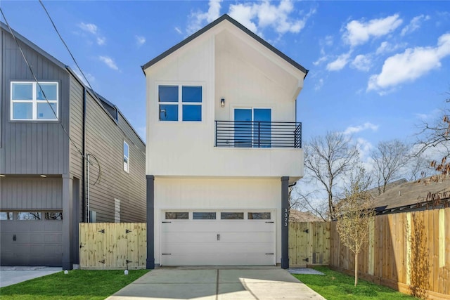 modern home featuring fence, an attached garage, driveway, and a balcony