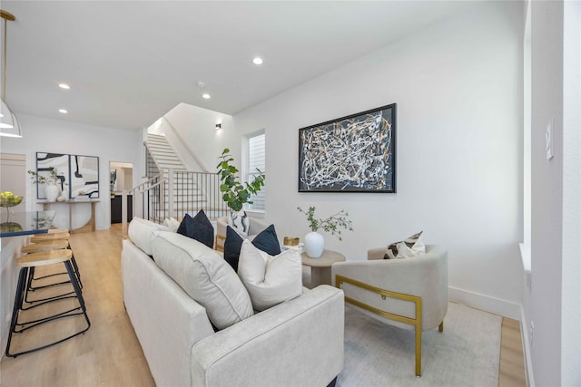 living area with recessed lighting, baseboards, stairway, and light wood-type flooring