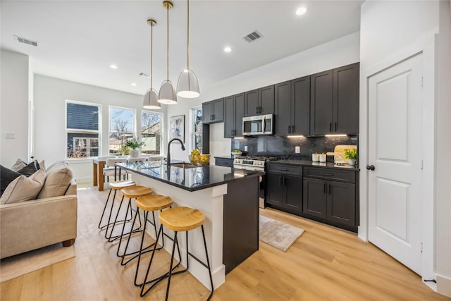 kitchen with dark countertops, appliances with stainless steel finishes, a sink, and visible vents