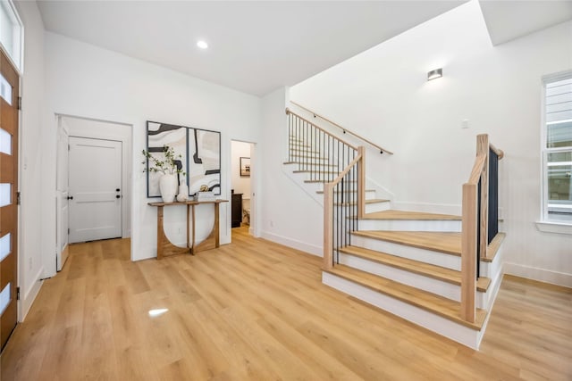 foyer entrance with plenty of natural light, baseboards, stairway, and light wood-type flooring