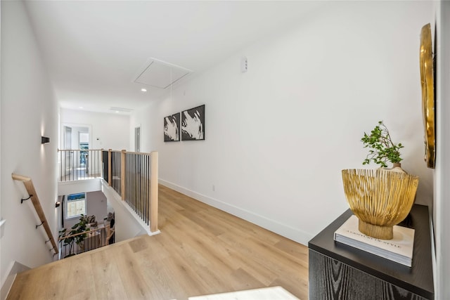 hallway with baseboards, attic access, wood finished floors, and an upstairs landing