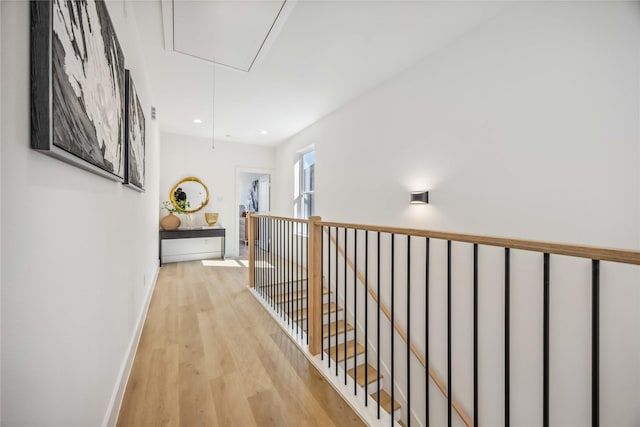 hall with attic access, wood finished floors, baseboards, an upstairs landing, and recessed lighting
