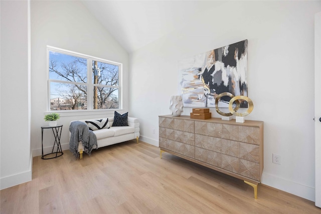 living area featuring baseboards, vaulted ceiling, and wood finished floors
