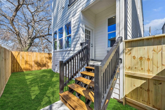 view of exterior entry with fence and a yard