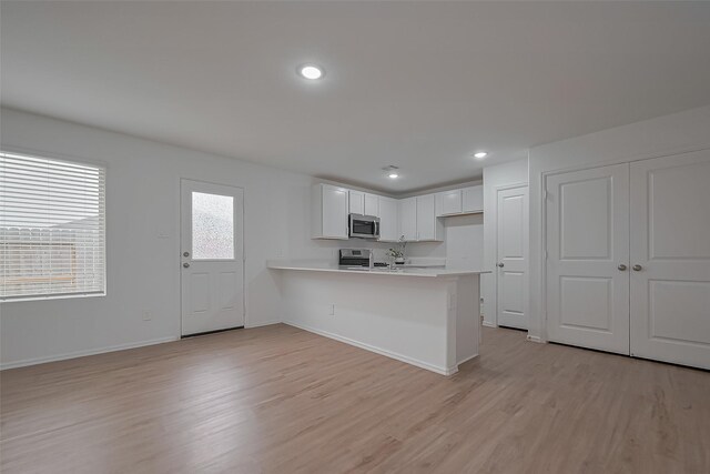 24119 Maple Turn Ln, Hockley, TX 77447 - kitchen with stainless steel microwave, stove, light countertops, and light wood-type flooring