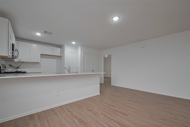 24119 Maple Turn Ln, Hockley, TX 77447 - kitchen with a sink, light wood-type flooring, a peninsula, stove, and visible vents