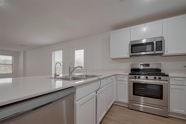 24119 Maple Turn Ln, Hockley, TX 77447 - kitchen with a sink, stainless steel appliances, light wood finished floors, light countertops, and white cabinetry