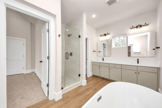 783 Mansfield St, Houston, TX 77091 - full bath with wood finished floors, a sink, a stall shower, a freestanding bath, and visible vents