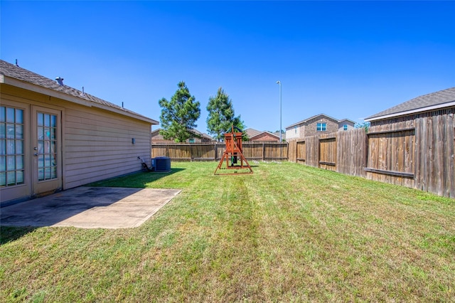 view of yard featuring central air condition unit, a patio area, a fenced backyard, and a playground