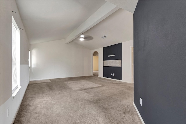 unfurnished room with lofted ceiling with beams, arched walkways, baseboards, carpet, and visible vents