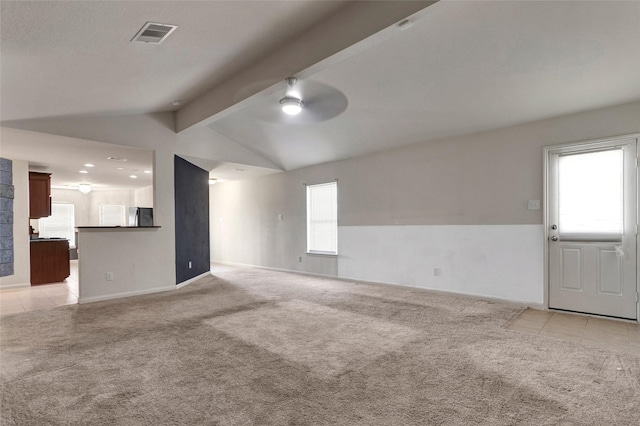 unfurnished living room featuring lofted ceiling with beams, light tile patterned flooring, light colored carpet, baseboards, and visible vents