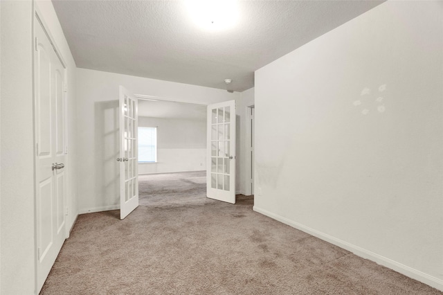 interior space with baseboards, french doors, carpet flooring, and a textured ceiling