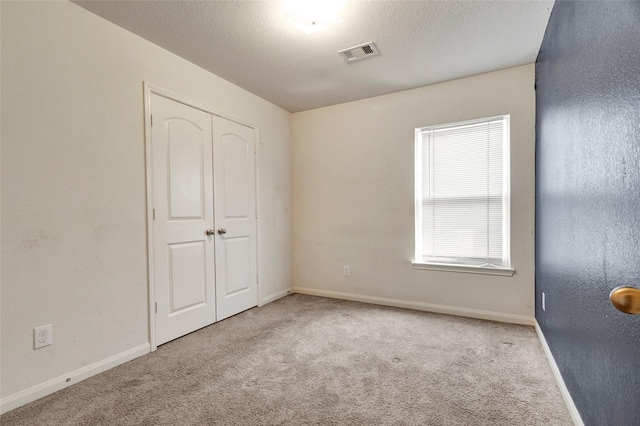 unfurnished bedroom featuring baseboards, visible vents, a closet, and carpet flooring