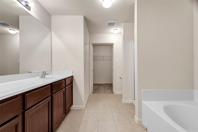 bathroom featuring a spacious closet, baseboards, a garden tub, and visible vents