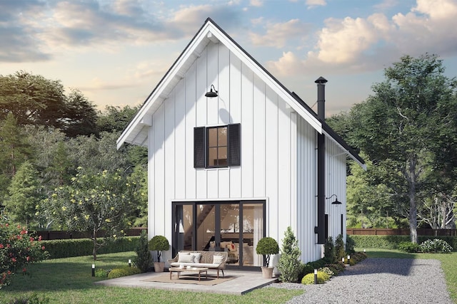 rear view of house with board and batten siding, a patio area, a lawn, and fence