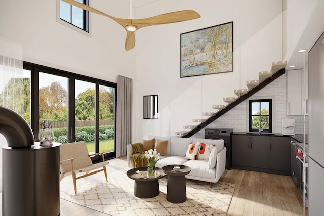 living area featuring light wood-type flooring, plenty of natural light, a towering ceiling, and stairway