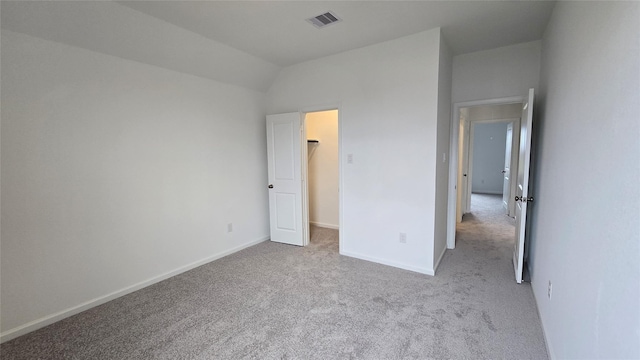 unfurnished bedroom featuring visible vents, baseboards, carpet flooring, and a walk in closet