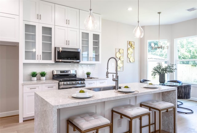 1114 Niagara St, Houston, TX 77051 - kitchen with backsplash, visible vents, a sink, light wood-style flooring, and appliances with stainless steel finishes