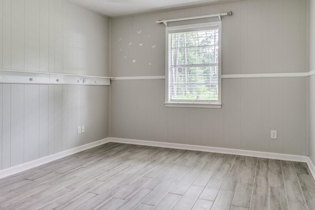 spare room with baseboards, wooden walls, and wood finished floors