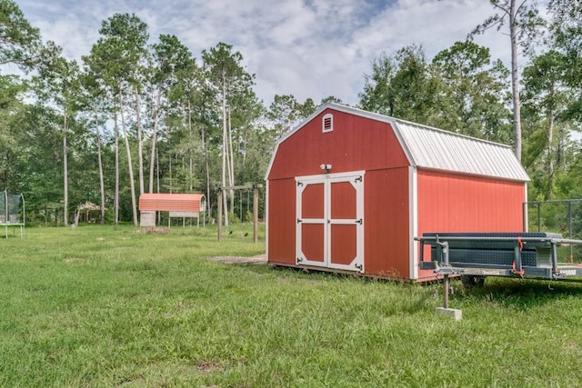 view of shed with fence and a trampoline