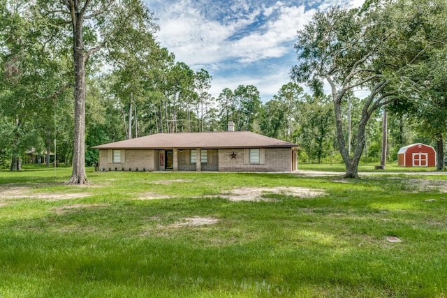 view of front of property featuring a storage shed, an outbuilding, a chimney, and a front yard