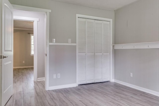 unfurnished bedroom with baseboards, wood finished floors, and a closet