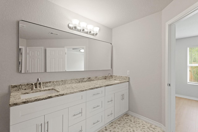 bathroom featuring visible vents, a sink, and baseboards