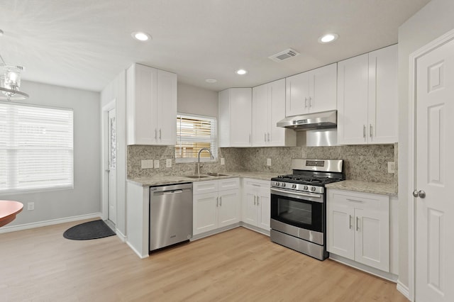 kitchen featuring under cabinet range hood, white cabinets, appliances with stainless steel finishes, and a sink