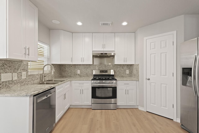 kitchen featuring visible vents, appliances with stainless steel finishes, a sink, light wood-style floors, and under cabinet range hood