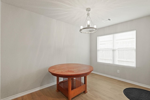 dining space featuring an inviting chandelier, baseboards, and light wood-type flooring