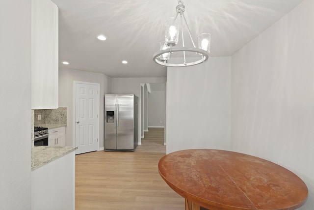 kitchen with a notable chandelier, appliances with stainless steel finishes, light wood-style floors, white cabinetry, and recessed lighting