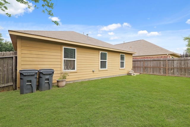 rear view of house with a fenced backyard and a lawn