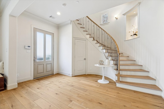 entryway with hardwood / wood-style flooring, visible vents, stairway, and crown molding