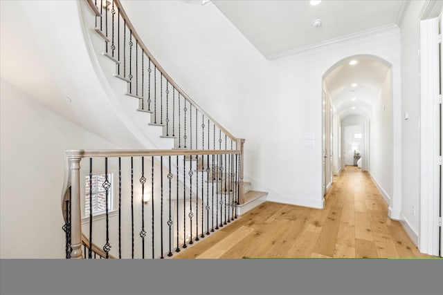 hall featuring hardwood / wood-style flooring, arched walkways, baseboards, ornamental molding, and recessed lighting