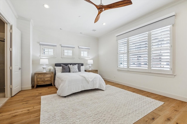 bedroom featuring multiple windows, light wood-style floors, and ornamental molding